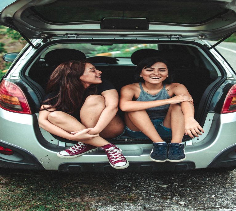 A couple of people that are sitting in the trunk of a carDescription automatically generated
